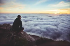 Man overlooking cloudy sky over sunrise