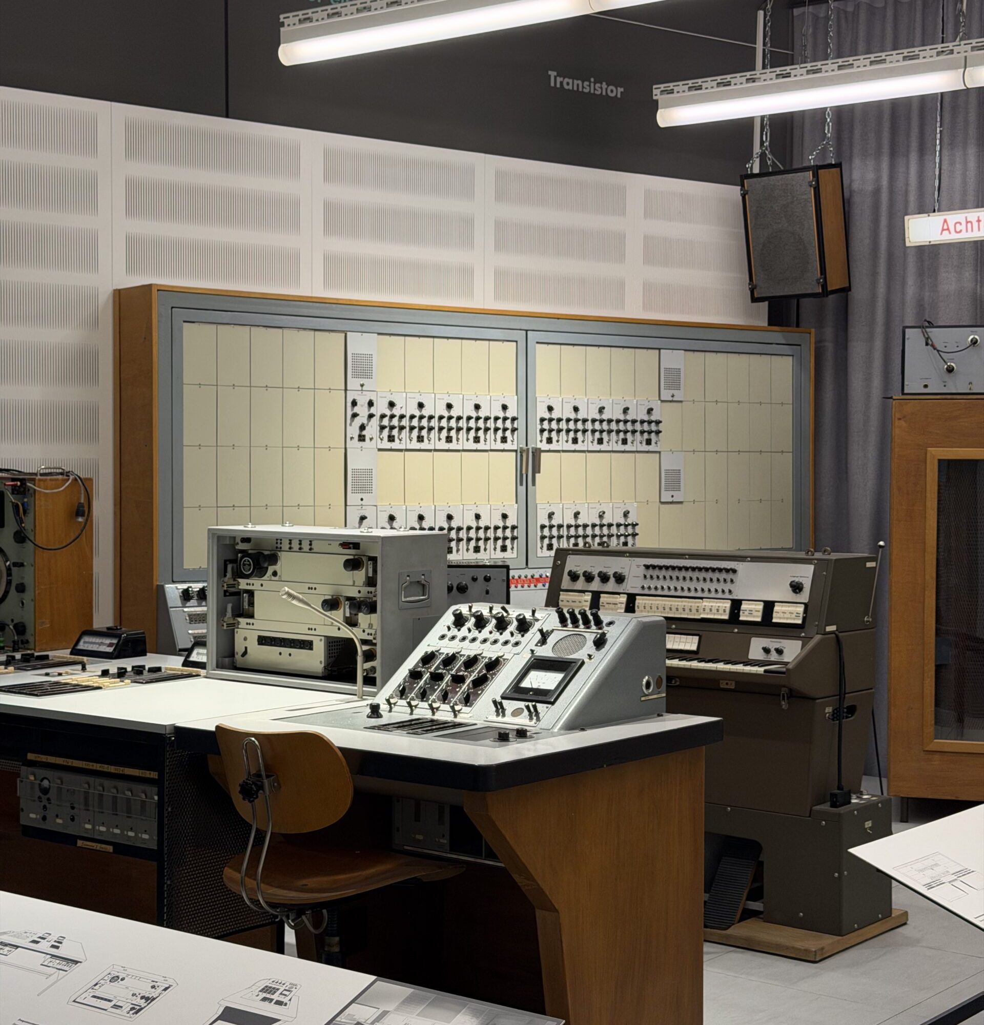 Vintage modular synthesizer rig on a workbench with multiple panels, knobs, and patch cables in a museum-style exhibit